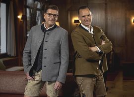 Peter Inselkammer und Heiko Buchta stehen in bayrischer Tracht gekleidet in der Lobby des Platzl Hotels.