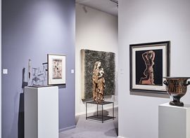 In einem Museumsraum werden Skulpturen, gerahmte Kunstwerke und antike Töpferwaren unter sanfter Beleuchtung ausgestellt