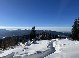 Winterliche Berglandschaft mit Hütte und Panoramablick auf die Alpen