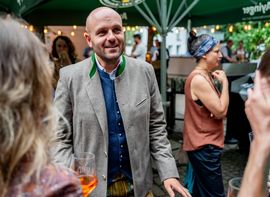 Bild vom Sommerfest, Mann im Vordergrund mit anderen Menschen im Hintergrund, sehr festlich 