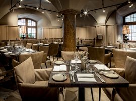 Zeitloses Speisezimmer mit Tischen und Sesseln im Restaurant Pfistermühle in München 