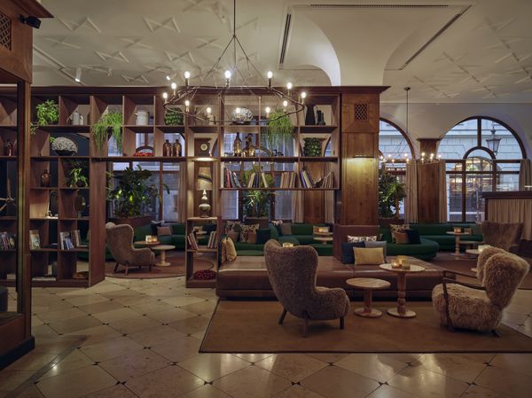 Eine stilvolle Hotel-Lounge mit bequemen Sesseln, Sofas, Bücherregalen aus Holz und sanfter Beleuchtung.