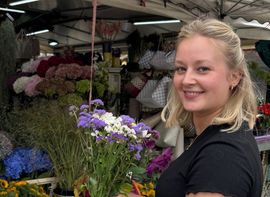 Eine junge Frau mit einem Blumenstrauß auf dem Viktualienmarkt