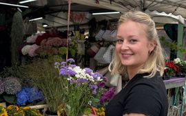 Eine junge Frau mit einem Blumenstrauß auf dem Viktualienmarkt