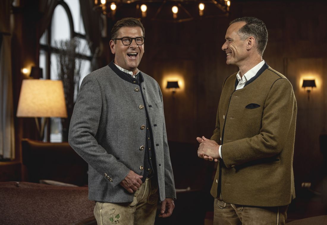 Zwei Hoteldirektoren in Tracht lachen herzlich in stilvoller Lounge