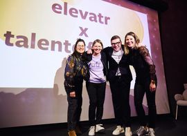 Vier Personen auf Bühne beim elevatr x talents Event, lachend vor Leinwand